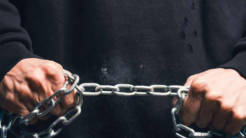 Close up of Hands of man Hold Iron Chain | Epoch Times Media