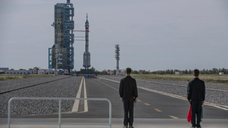 Рабочие стоят рядом с пилотируемым космическим кораблем «Шэньчжоу-12» Китайского агентства пилотируемых космических полетов на борту ракеты «Лонг Марш-2Ф» перед запуском, на борту которой находятся три китайских космонавта, на космодроме Цзюцюань в провинции Ганьсу, Китай, 17 июня 2021 года. (Кевин Фрейер/Getty Images)