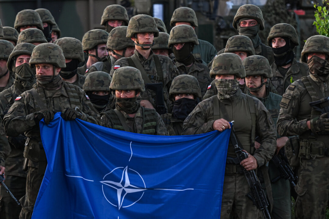 Польские военнослужащие держат флаг НАТО во время фотосессии после учений с участием многонациональной боевой группы НАТО eFPon на полигоне в Оржише (Польша) 3 июля 2022 года. (Омар Маркес/Getty Images) | Epoch Times Media