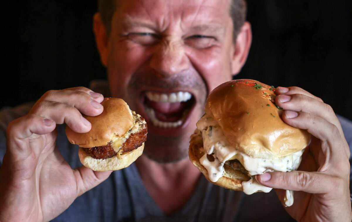 Александр Ринглеб, владелец Burgermeister Miami, демонстрирует размер слайдера по сравнению с гамбургером стандартного размера в своем ресторане в Брикелле. (Карл Жюст/Miami Herald/TNS)