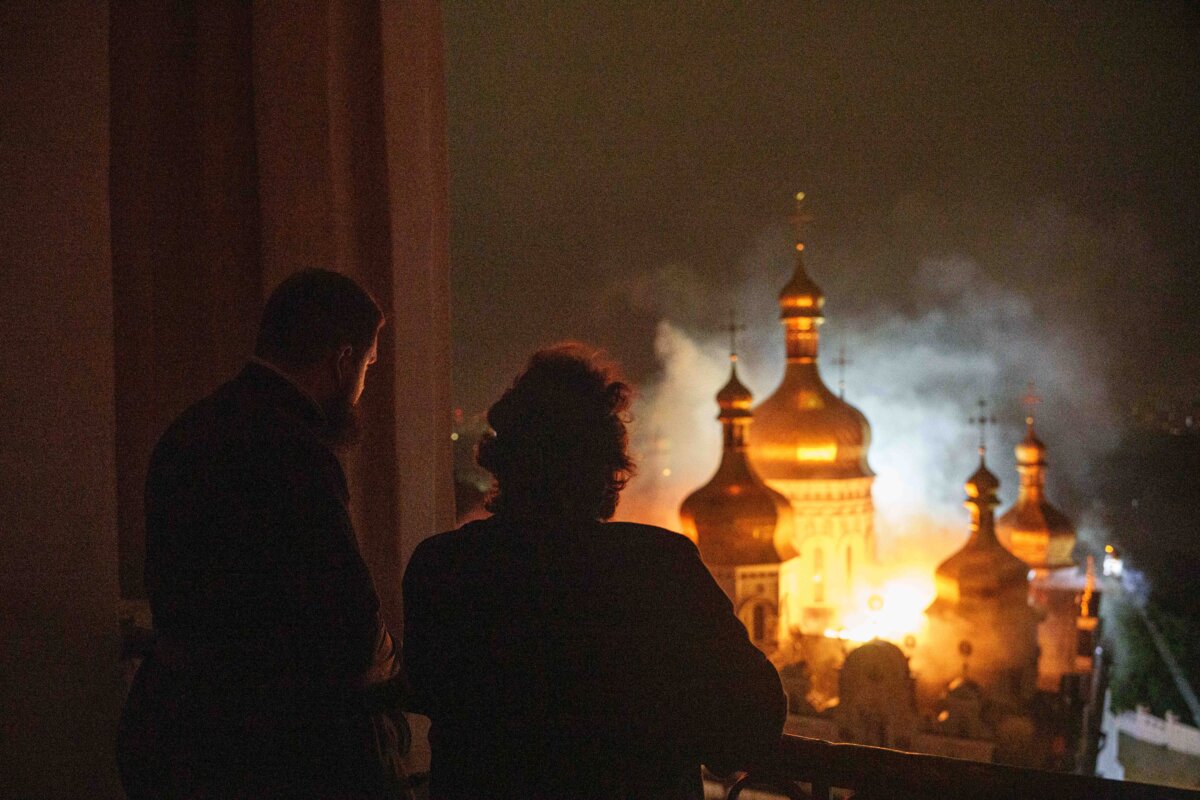 Епископ Авраамий (справа) Киево-Печерской лавры Православной Церкви Украины смотрит на горящий Успенский собор Киево-Печерской лавры, также известный как Печерский монастырь, во время российского удара по Киеву, Украина, 15 июня 2026 года. (Фото Евгения Малолетки/AP)