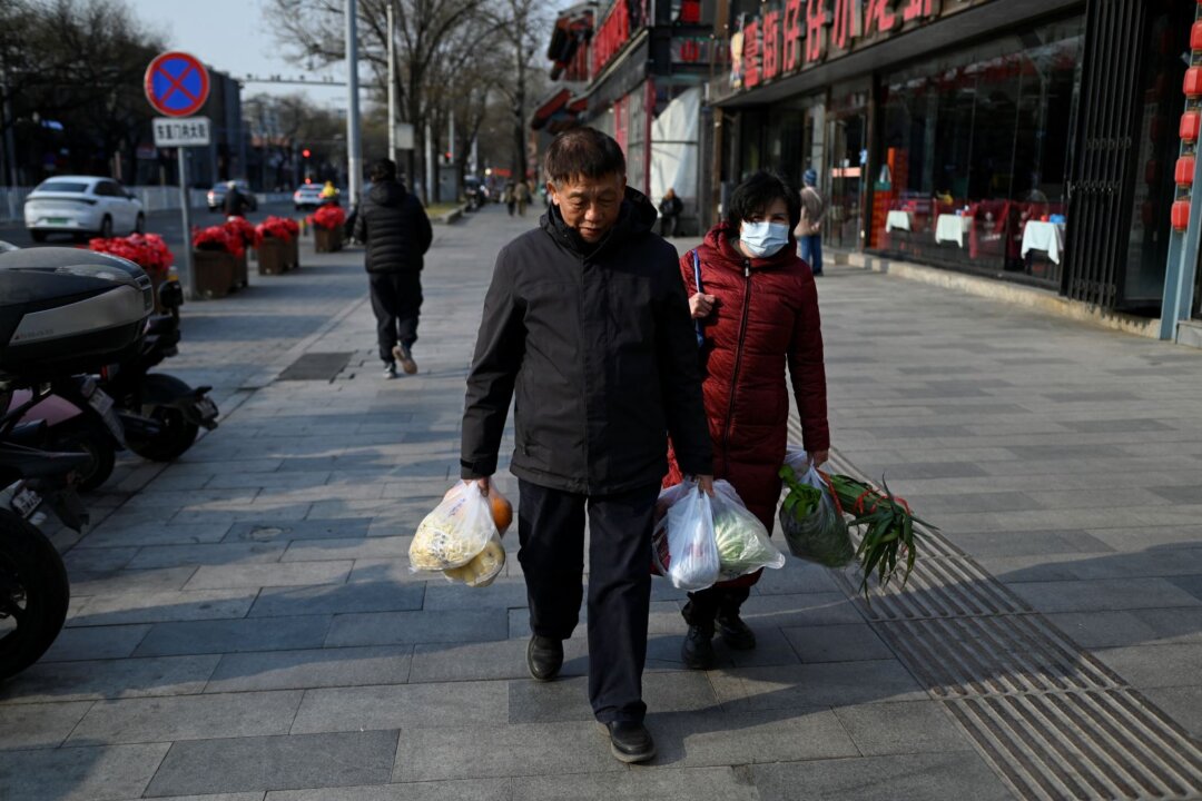 22 декабря 2025 года пожилая пара с продуктами проходит мимо ресторана в Пекине. (Ван Чжао/AFP via Getty Images) | Epoch Times Media