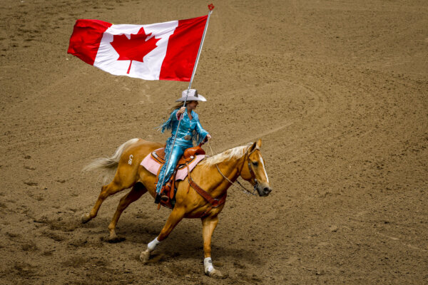 Принцесса Calgary Stampede Sarah O'Brien несёт канадский флаг во время исполнения национального гимна перед началом родео на Calgary Stampede в Калгари, Альберта, 3 июля 2026 года. (The Canadian Press/Jeff McIntosh)