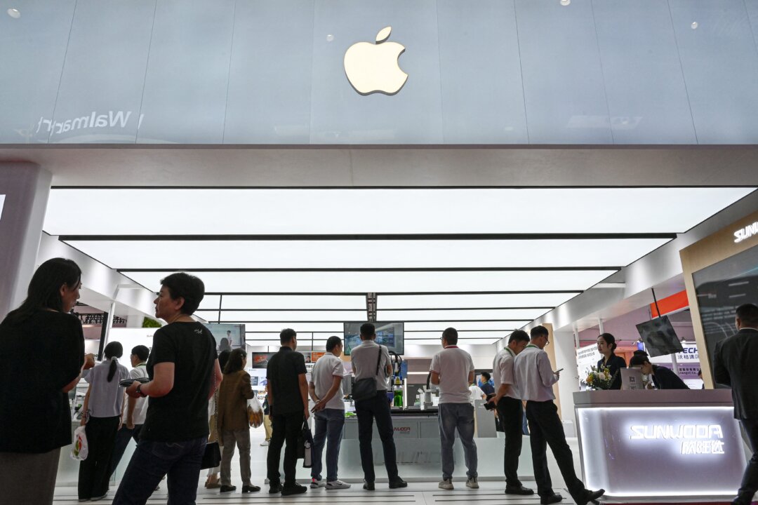 Люди проходят мимо стенда компании APPLE и ее поставщиков, включая Sunwoda, JUSTECH и Innovation Group, во время Китайской международной выставки цепочек поставок (CISCE) в Пекине 17 июля 2025 года. (Jade Gao/AFP via Getty Images) | Epoch Times Media