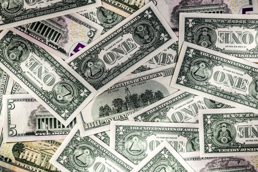 Разбросанная куча различных долларовых купюр: номиналом 1, 5, 20 и 100 долларов. | Epoch Times Media
